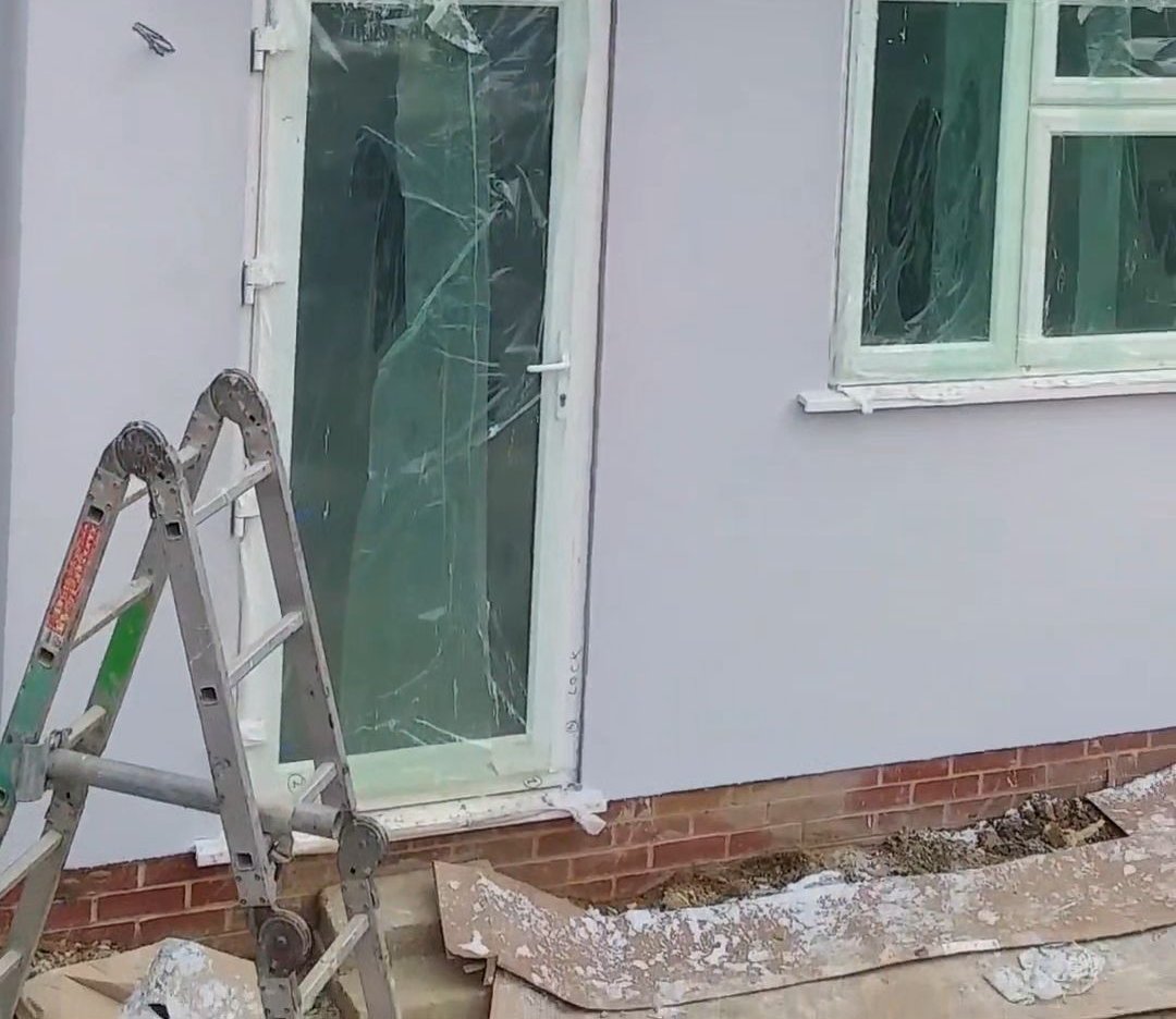 Rendered exterior wall with masked windows and a ladder