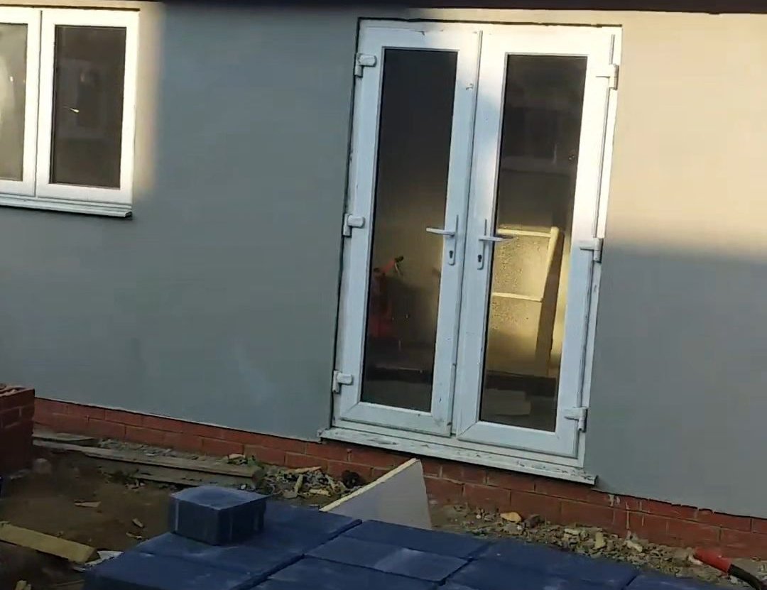 Rendered exterior wall with white double doors